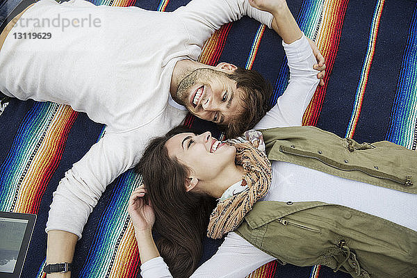 Hochwinkelansicht eines liebenden Paares  das sich auf einer Decke liegend anschaut