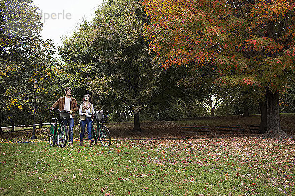 Paar redet beim Spaziergang mit Fahrrädern im Park