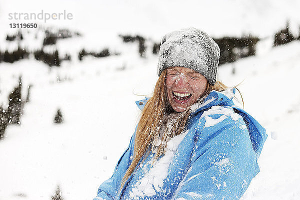 Fröhliche Frau mit Schnee bedeckt