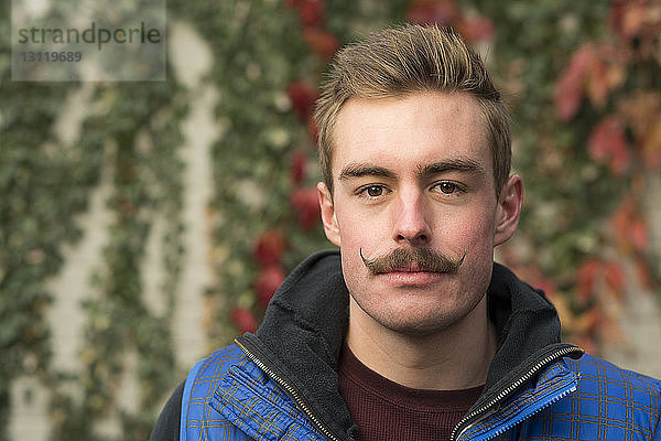 Porträt eines selbstbewussten Mannes mit Schnurrbart im Hinterhof