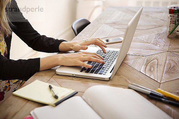 Beschnittenes Bild einer Geschäftsfrau mit Laptop am Schreibtisch im Büro
