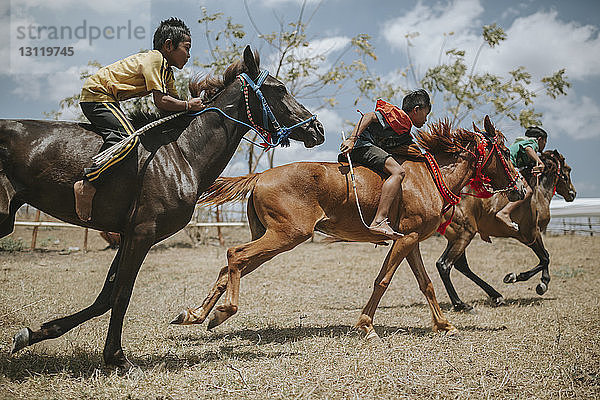 Seitenansicht von Kindern auf Rennpferden beim Pferderennen