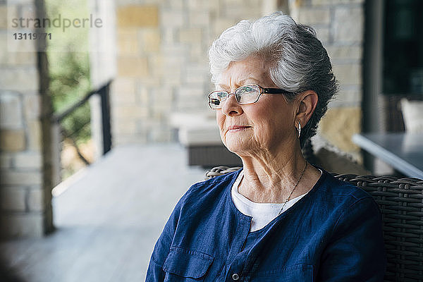 Nachdenkliche ältere Frau sitzt auf der Veranda