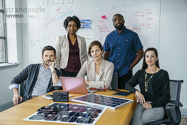 Portrait von Geschäftsleuten durch Solarpanel-Modelle auf dem Schreibtisch