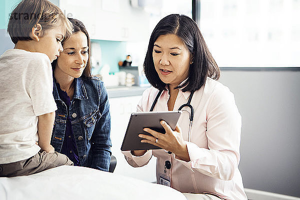 Arzt erklärt Familie in Klinik den Bericht auf Tablet-Computer