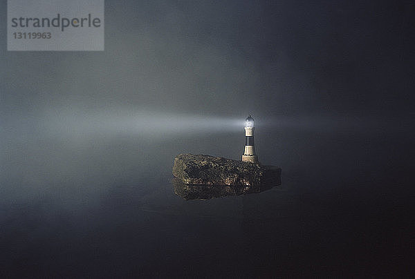 Beleuchteter Leuchtturm auf Insel gegen den Himmel bei Nacht