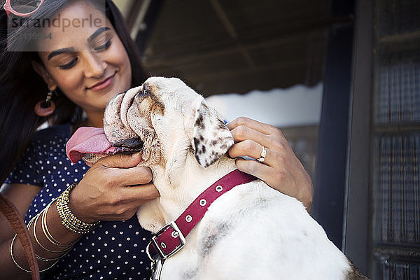 Lächelnde Frau berührt Bulldogge gegen Fenster