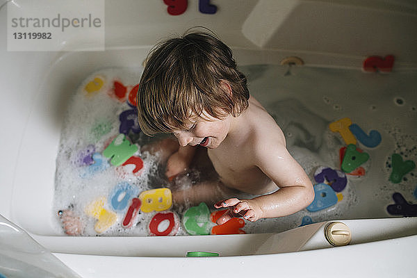 Schrägansicht eines Jungen  der mit Spielzeug in der Badewanne spielt