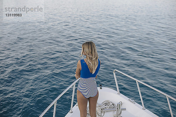 Rückansicht einer Frau  die Badebekleidung trägt  während sie auf einer Yacht auf See steht