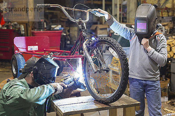 Vater und Sohn bauen während der Arbeit in der Werkstatt ein Dreirad