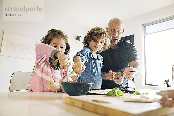 Vater hilft Sohn und Tochter bei der Zubereitung von Essen zu Hause