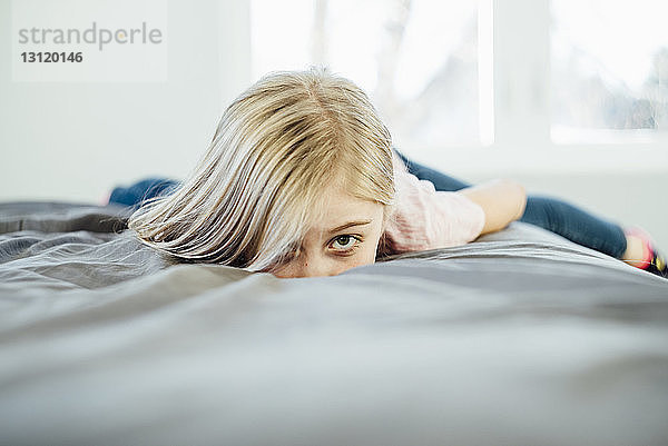 Porträt eines zu Hause auf dem Bett liegenden Mädchens