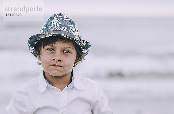 Porträt eines Jungen  der am Strand gegen den Himmel steht