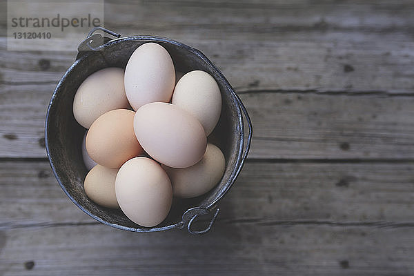 Draufsicht auf Eier im Eimer auf Holztisch