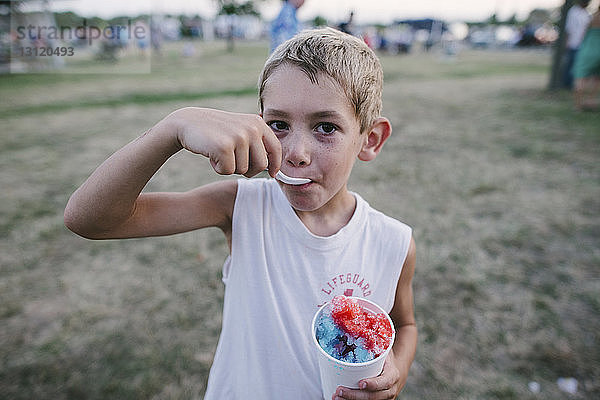 Porträt eines Jungen  der auf dem Feld Crushed-Ice isst