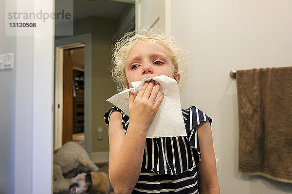 Nahaufnahme eines Mädchens  das vor Zahnschmerzen weint  während es zu Hause an der Wand steht