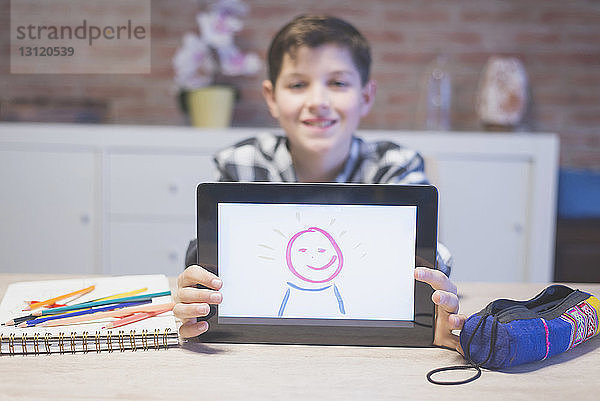 Porträt eines lächelnden Jungen  der zu Hause auf einem Tablet-Computer zeichnet