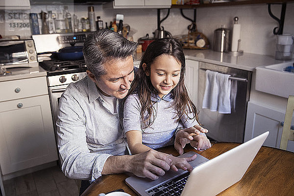 Hochwinkelaufnahme von Vater und Tochter am Laptop in der Küche zu Hause