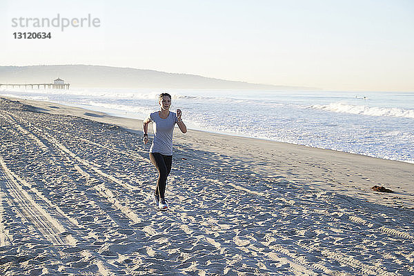 Frau in voller Länge am Strand joggend