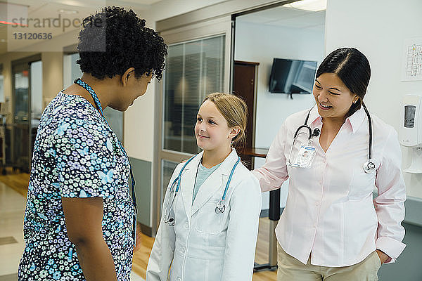 Mädchen mit Laborkittel beim Blick zum Kinderarzt im Krankenhauskorridor