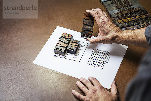 Beschnittenes Bild eines Mannes  der in der Werkstatt Buchdruckholz hält