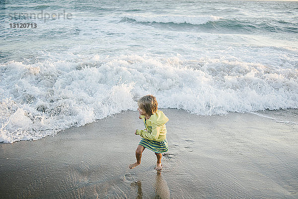 Hochwinkelaufnahme eines Mädchens  das am Strand an der Küste läuft