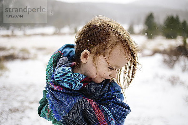 Glückliches Mädchen im Winter in eine Decke gehüllt