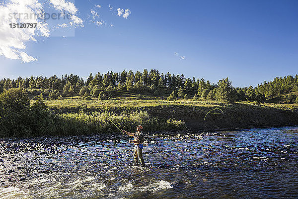 Mann fischt im Fluss gegen den Himmel