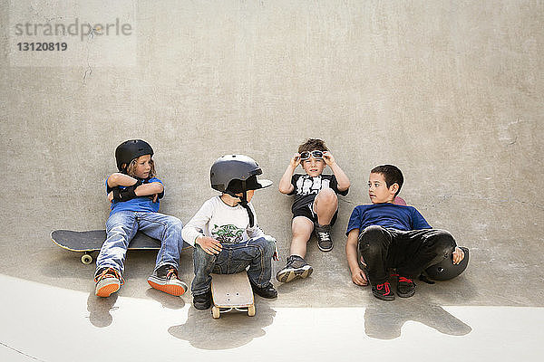 Jungen unterhalten sich  während sie auf der Skateboard-Rampe sitzen