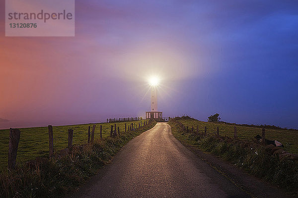 Beleuchteter Lastres-Leuchtturm gegen dramatischen Nachthimmel