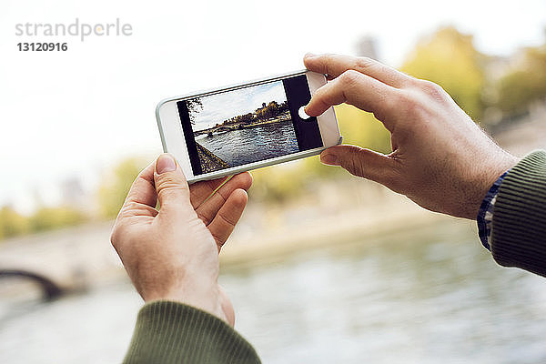 Ausgeschnittene Hände fotografieren Fluss durch Smartphone