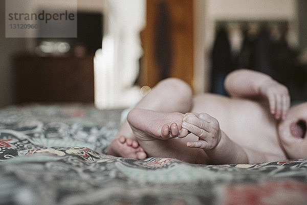 Niedere Sektion eines hemdlosen Mädchens  das zu Hause auf dem Bett liegt