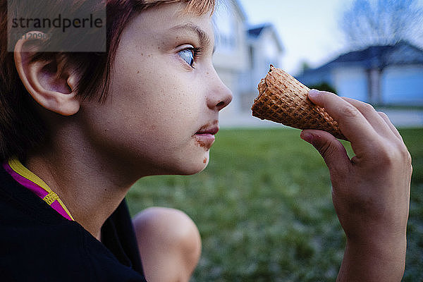Seitenansicht eines Mädchens  das Eiswaffeln betrachtet  während es im Hof sitzt