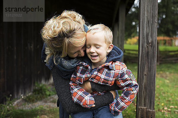 Verspielte Mutter umarmt Sohn auf dem Bauernhof