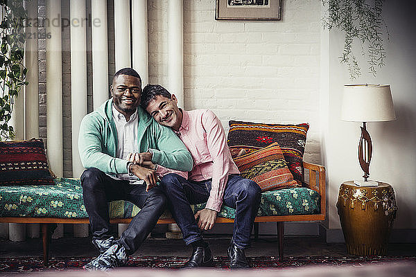 Ganzfigur eines liebenden schwulen Paares  das zu Hause auf einer Chaiselongue sitzt