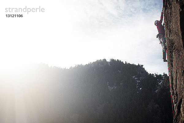 Seitenansicht eines Mannes  der auf einem felsigen Berg gegen den Himmel klettert