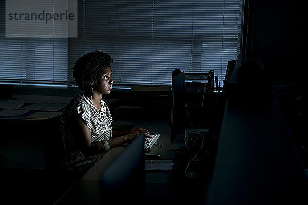 Seitenansicht einer Geschäftsfrau  die am Desktop-Computer am Schreibtisch im Büro arbeitet