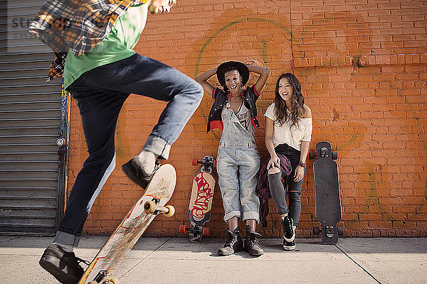 Freundinnen beobachten Mann bei Skateboard-Stunt