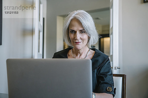 Seriöse Geschäftsfrau  die im Büro an einem Laptop-Computer arbeitet