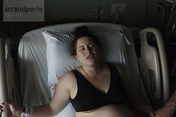 Hochwinkelaufnahme einer schmerzhaften schwangeren Frau  die auf einem Krankenhausbett liegt