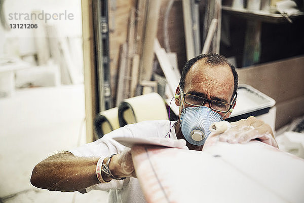 Handwerker  der in einem Workshop ein Surfbrett herstellt