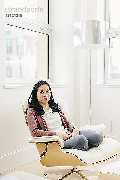 Porträt einer selbstbewussten Geschäftsfrau  die auf einem Stuhl sitzt