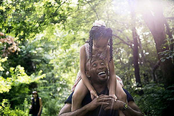 Glücklicher Vater trägt Tochter an sonnigem Tag im Park