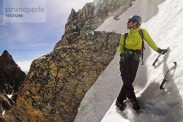 Eiskletterer schaut weg  während er auf dem Berg steht