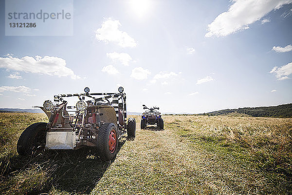 Geländewagen und Quadbike auf Grasfeld gegen den Himmel