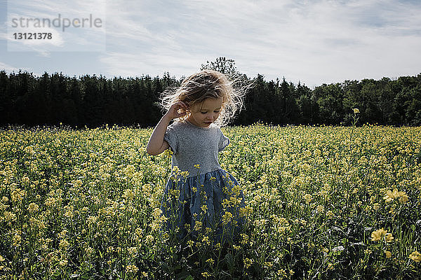 Süßes Mädchen steht inmitten von Pflanzen gegen den Himmel