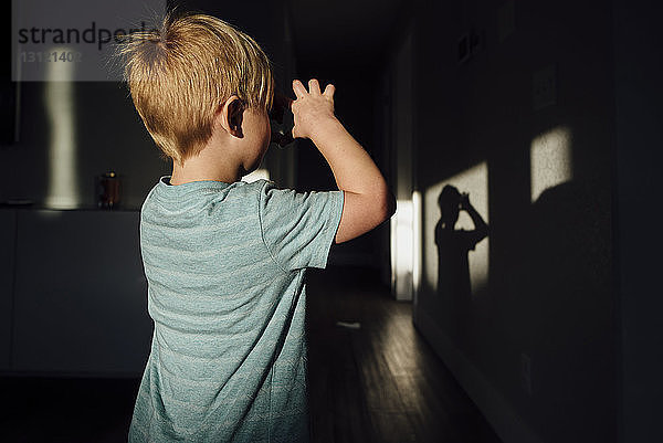 Rückansicht eines Jungen  der in der Dunkelkammer mit Sonnenlicht spielt