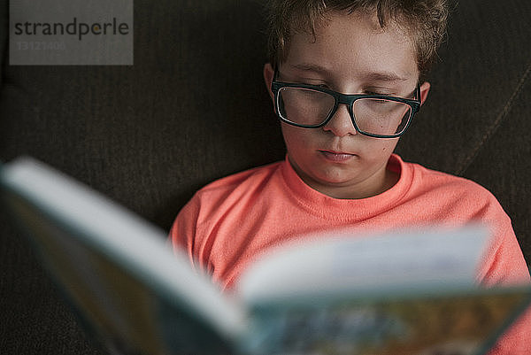 Nahaufnahme eines Jungen  der lernt  während er zu Hause auf dem Sofa sitzt