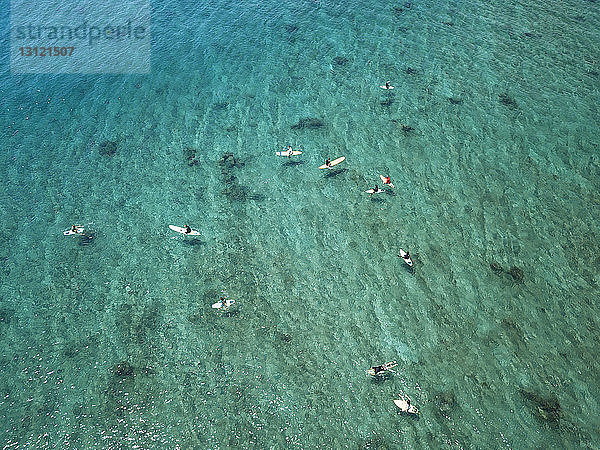 Luftaufnahme von Menschen  die am sonnigen Tag auf dem Meer surfen