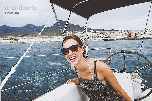 Lächelnde Frau sitzt in einem Boot  das auf See fährt